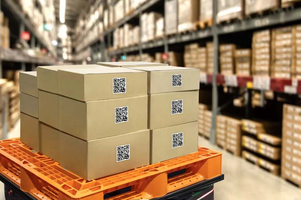 Boxes stacked on an orange cart in a large warehouse with racks in background
